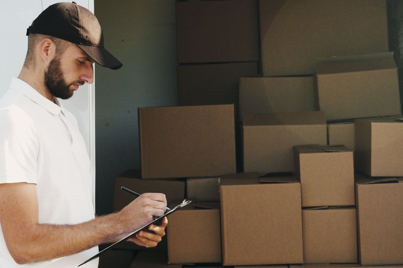 A mover working through the inventory sheet against a stacked wall of packed cartons.